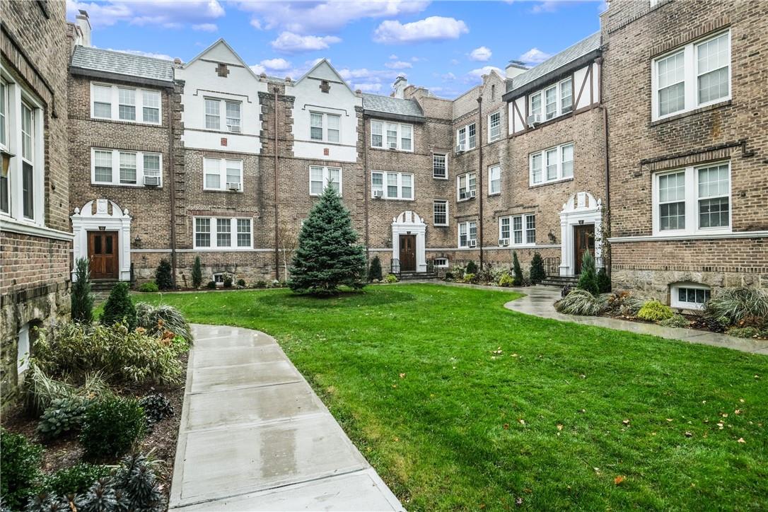 Brick apartment building enclosing a landscaped courtyard with a central lawn and curved walkways.
