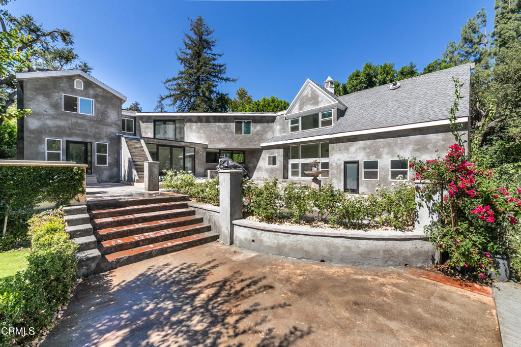 Gray two-story house with broad front steps and landscaped garden beds.