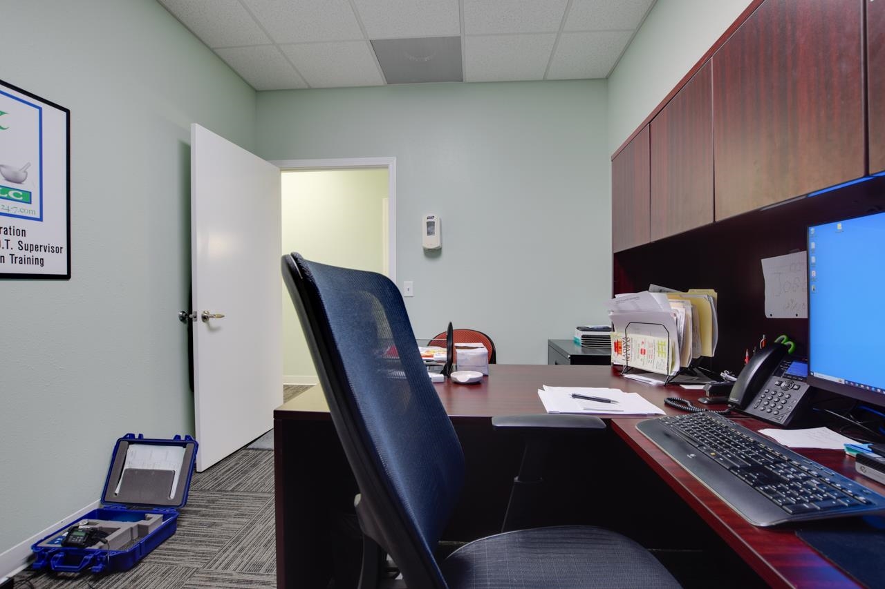 Office workstation with overhead cabinets, computer, desk phone, and an open doorway.