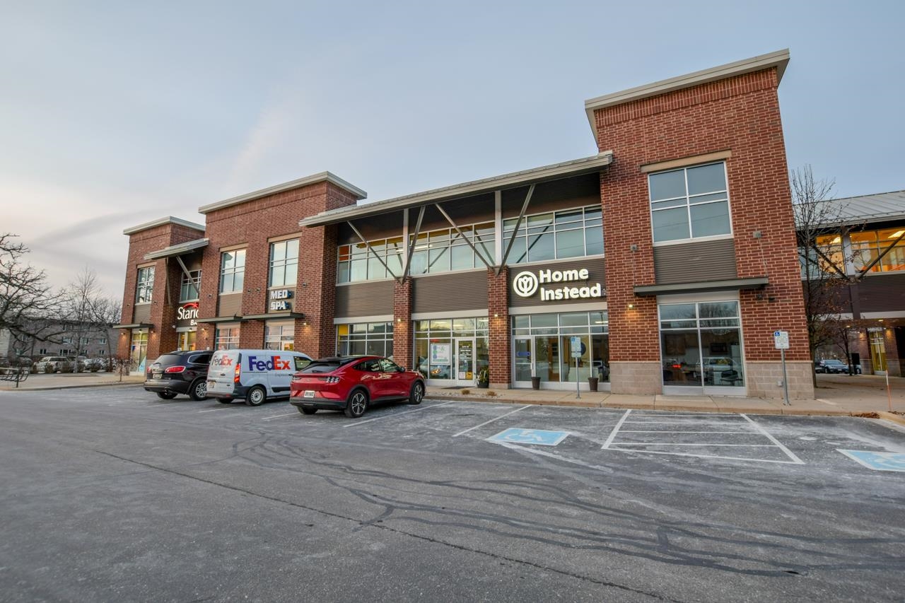 Red-brick commercial building with Home Instead storefront, large windows, and accessible parking spaces.