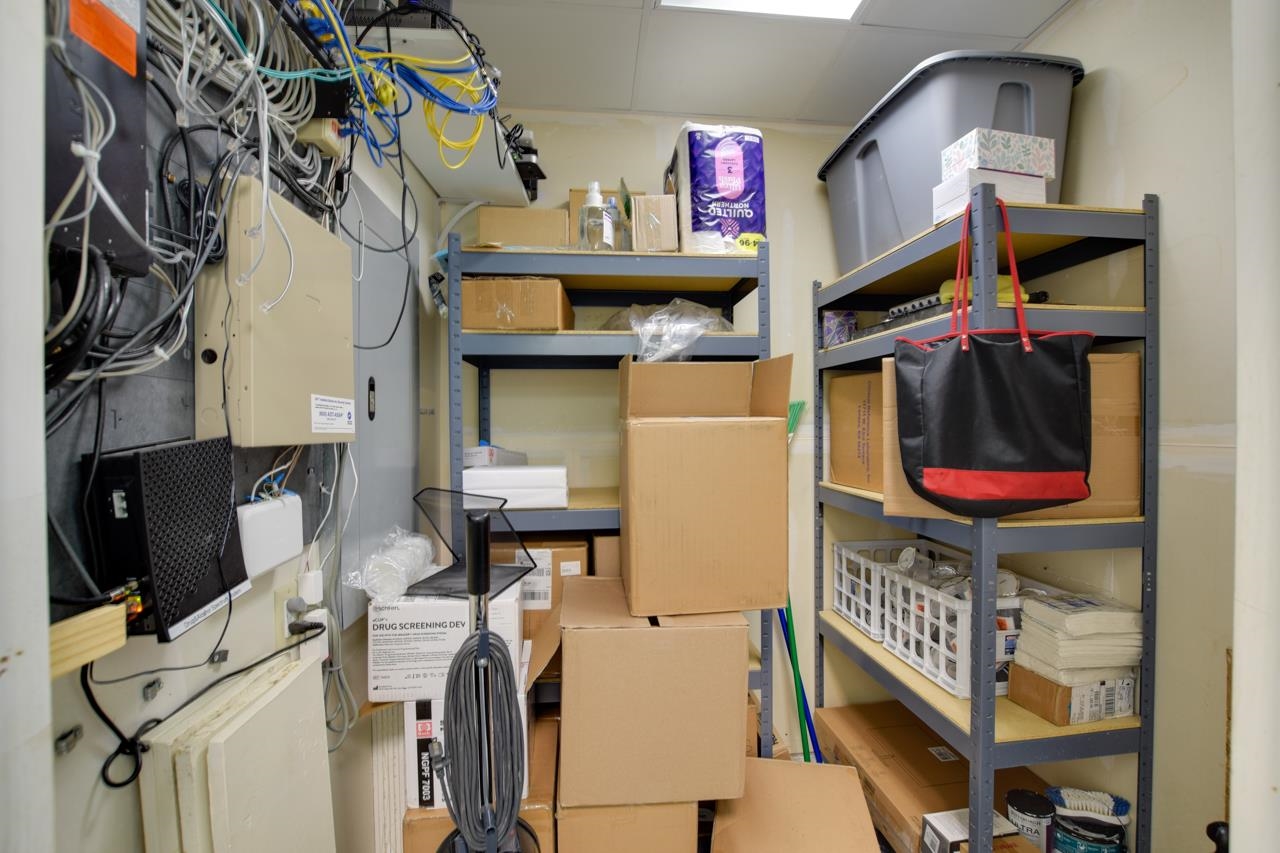 Storage room with exposed network cables, metal shelving, and stacked cardboard boxes.