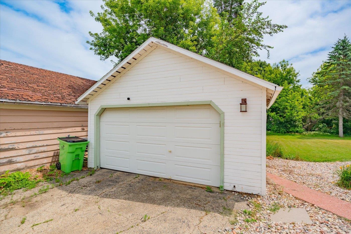 Detached white garage with pale green trim beside a concrete driveway and lawn.