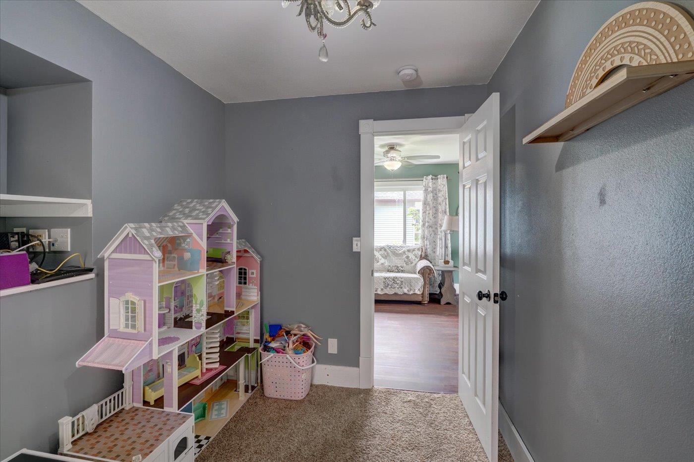 Child’s playroom with a large purple dollhouse and an open doorway to a bedroom.