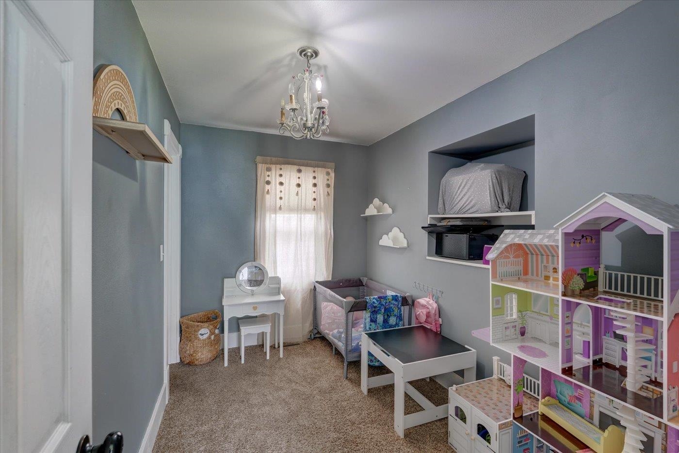 Child's playroom with colorful dollhouses, a small vanity, and a child-sized sofa.