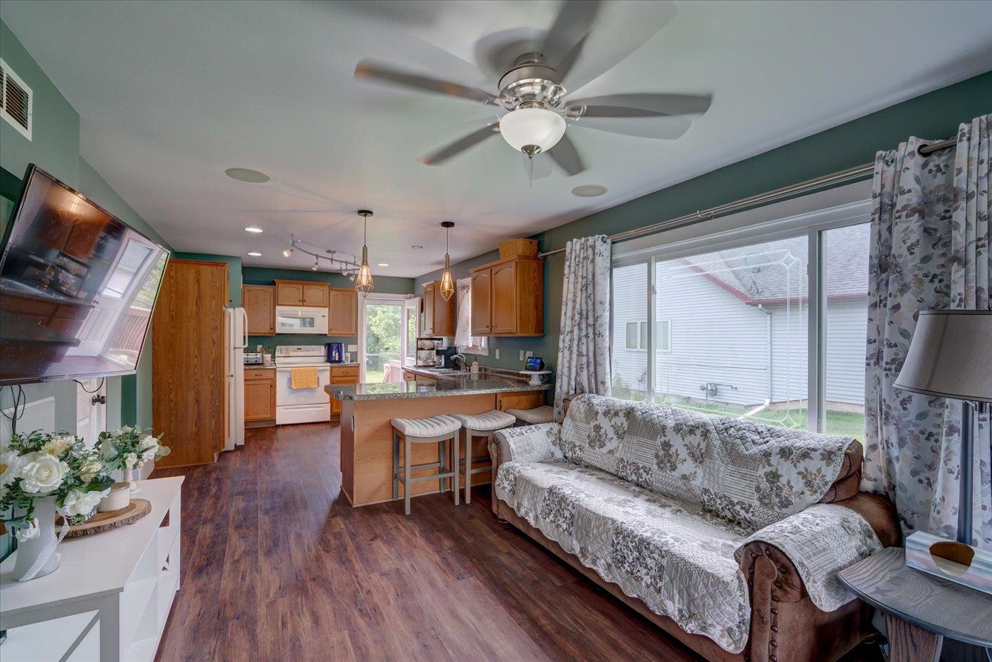 Open living room and kitchen with a wood-cabinet island, patterned sofa, and sliding glass doors.