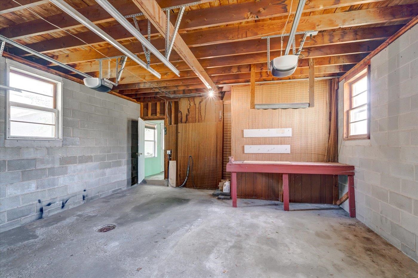 Garage with exposed ceiling joists, concrete block walls, and a red workbench.