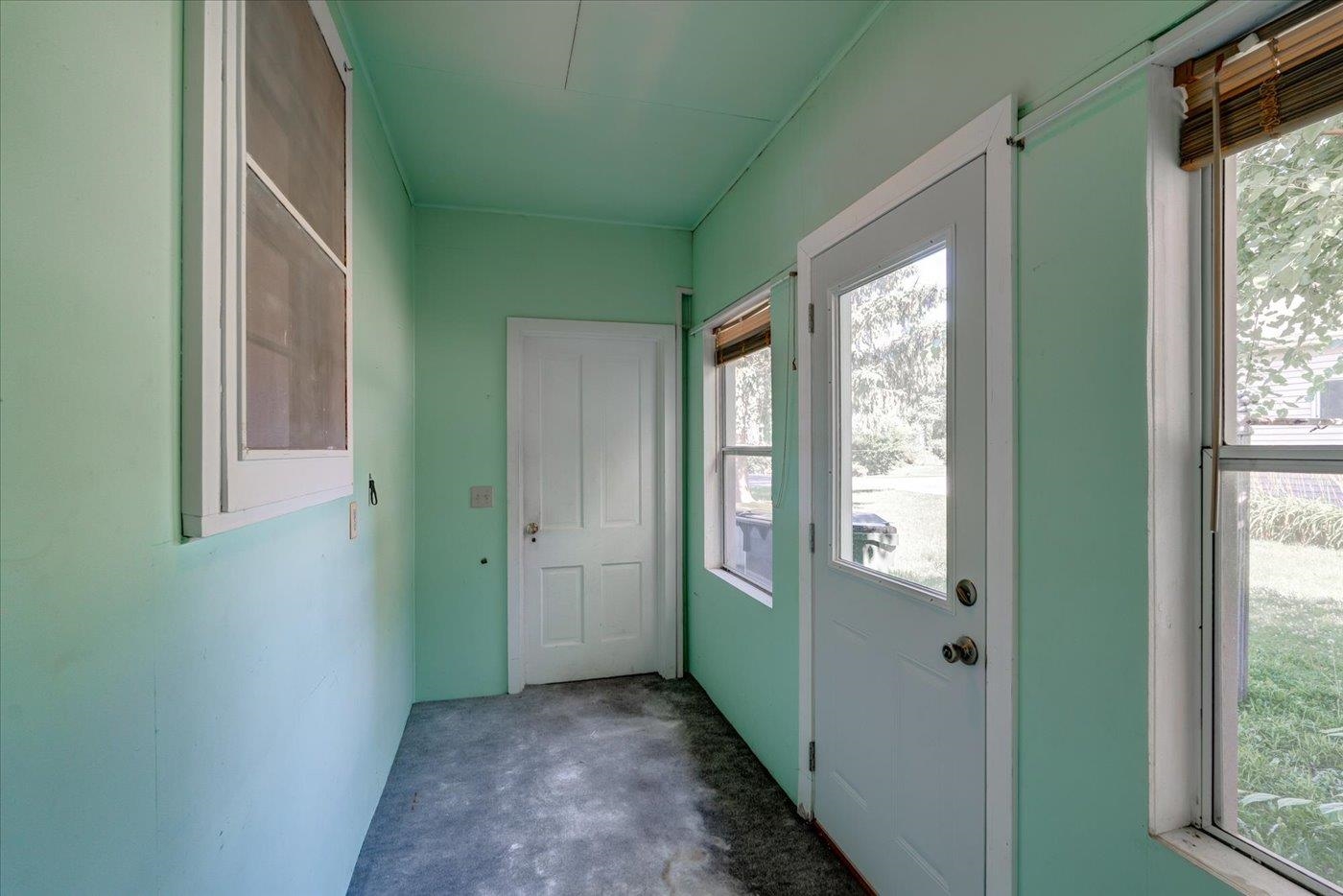 Narrow mint-green entryway with a glass-panel exterior door and windows.