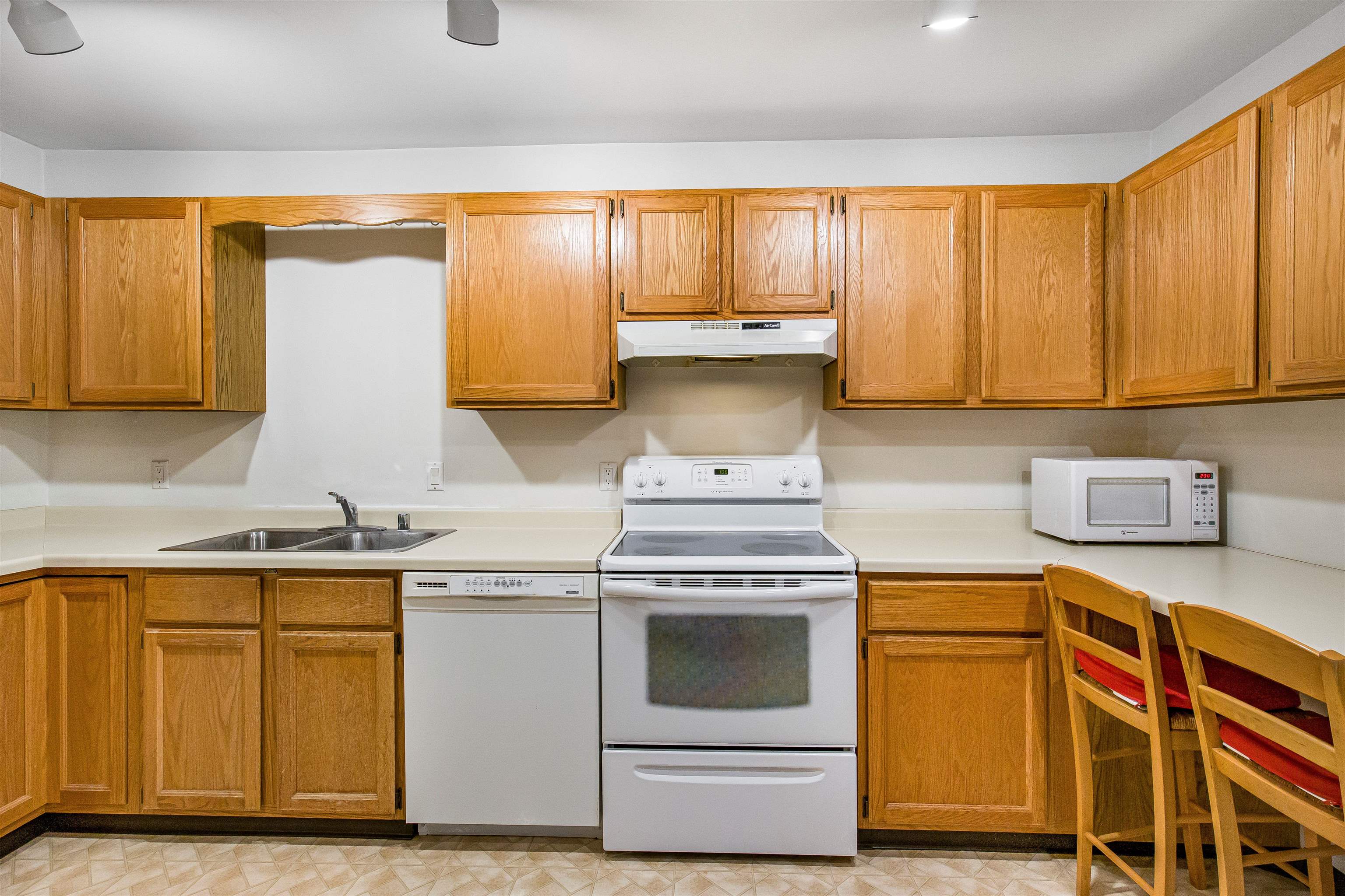 Kitchen with honey-colored cabinets, white countertops, and a central electric range.