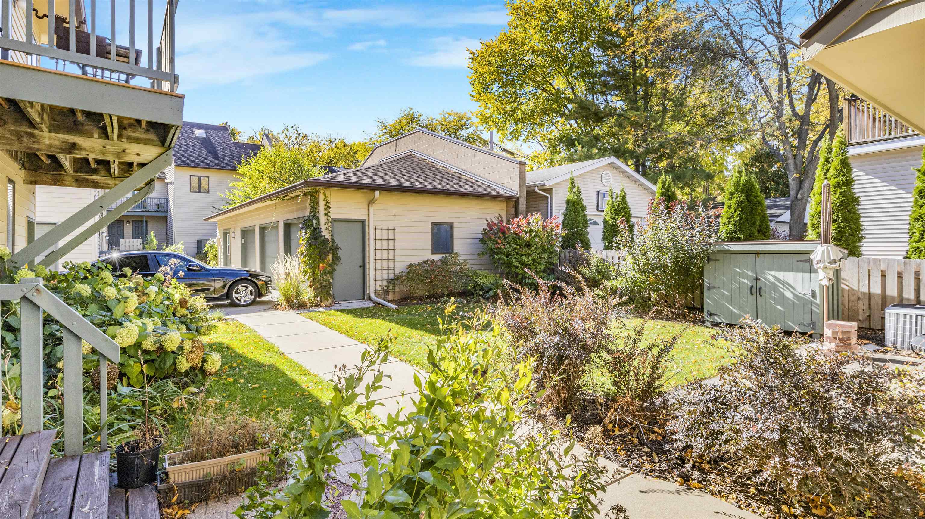 Landscaped backyard with a walkway to a detached garage, garden beds, and a wooden deck.