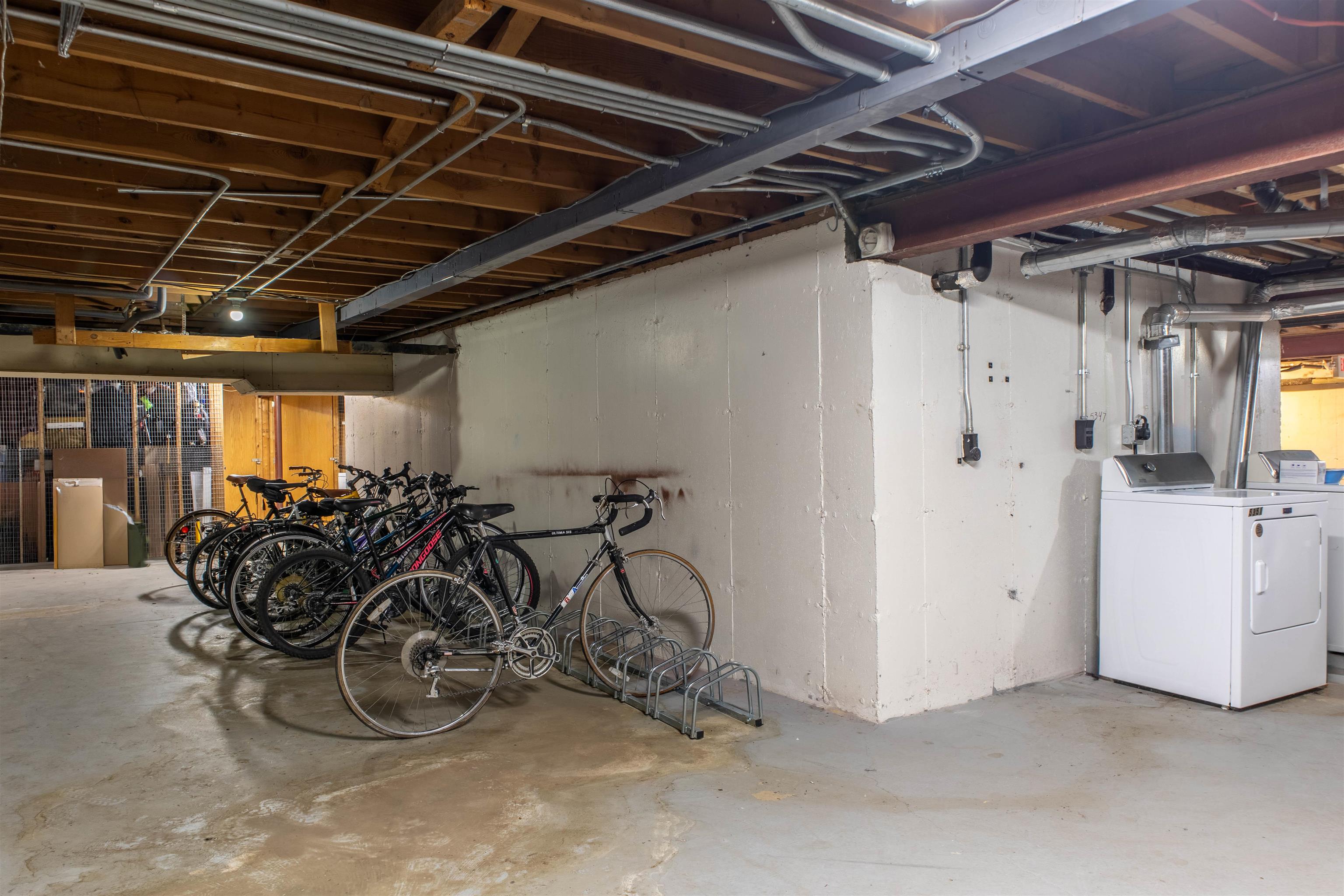 Basement with bicycle storage, exposed ceiling joists, and a washer and dryer.