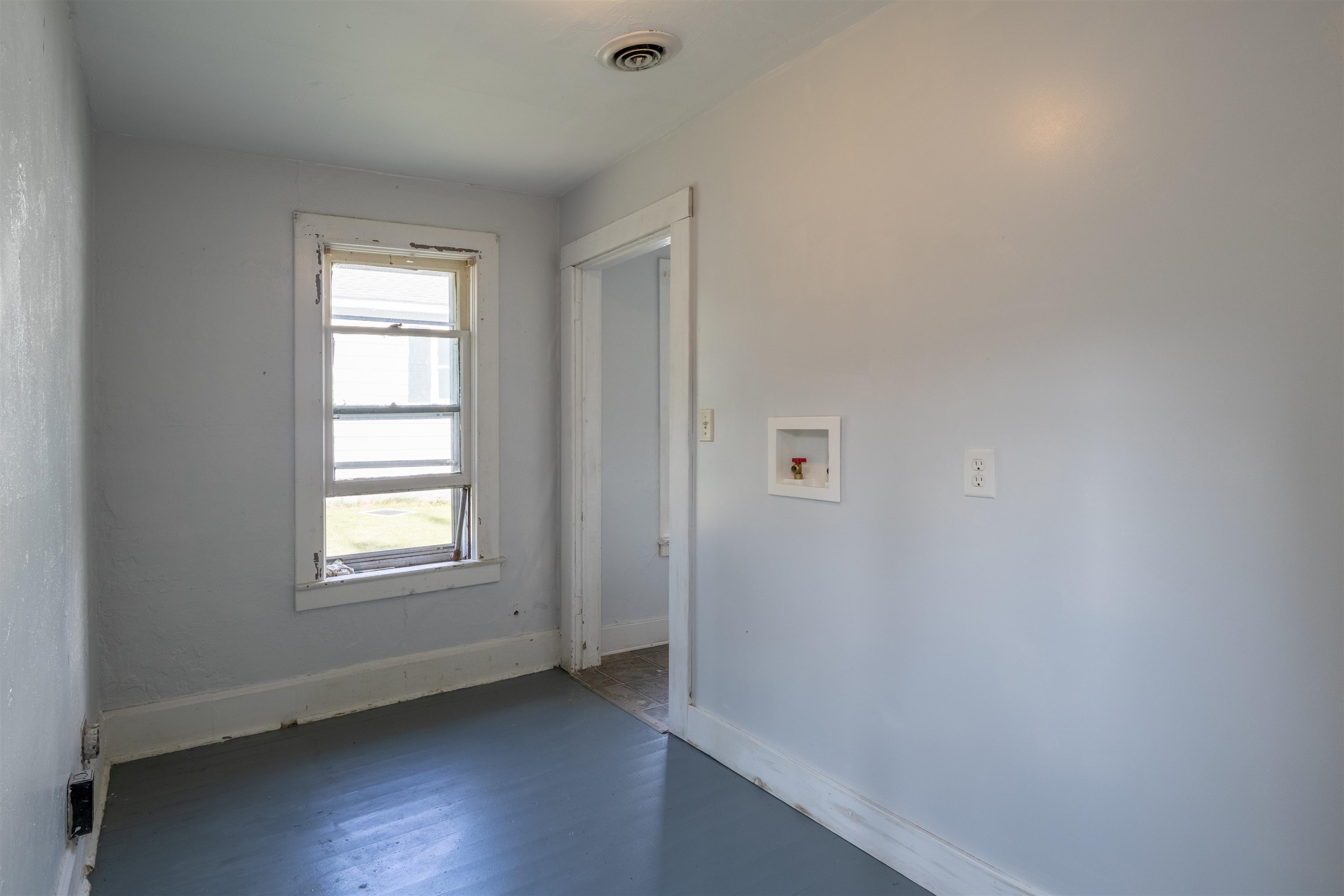 Empty room with washer hookups, a window, and blue-gray flooring.