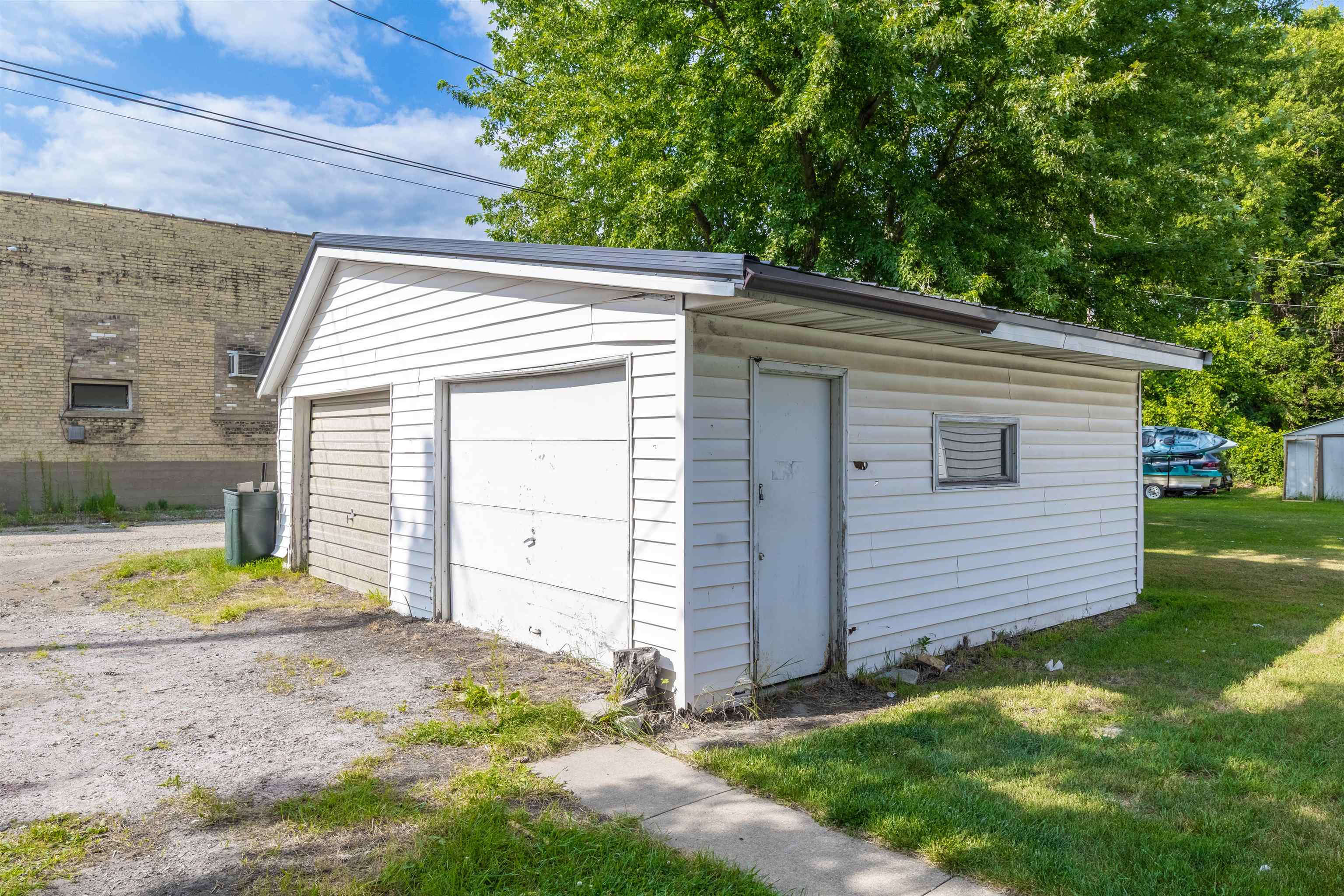White detached garage with two garage doors, a side entry door, and a small window.