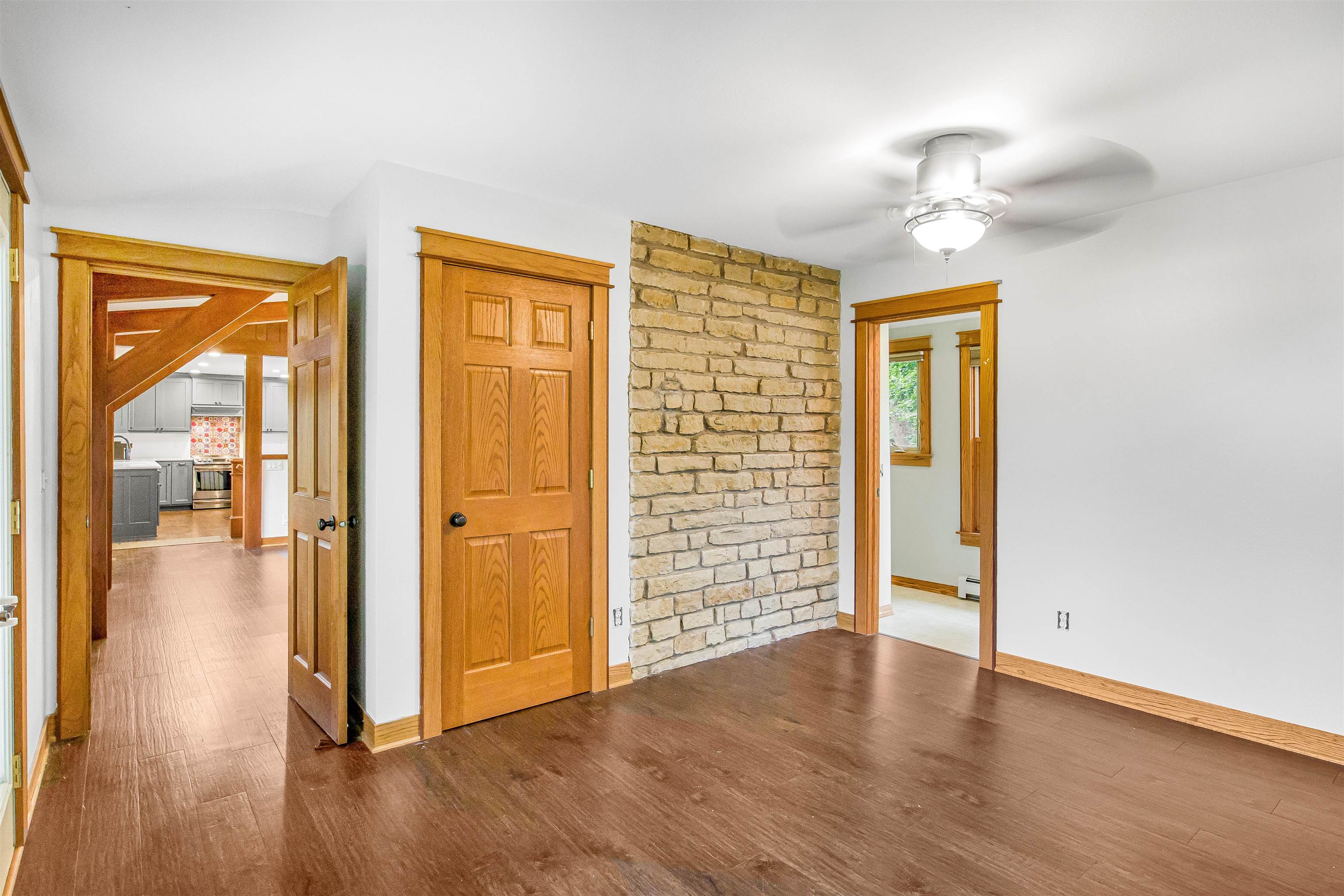 Vacant room with a stone accent wall, dark wood floors, and warm wood trim.