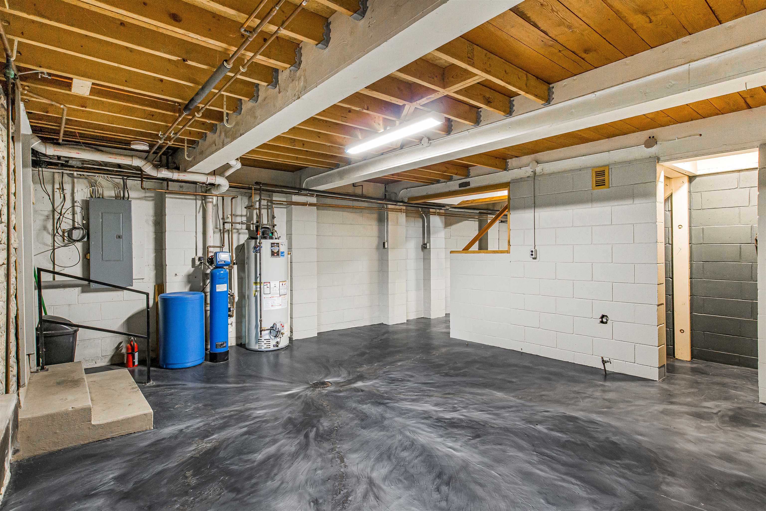 Unfinished basement with exposed ceiling joists, a concrete floor, and utility equipment.