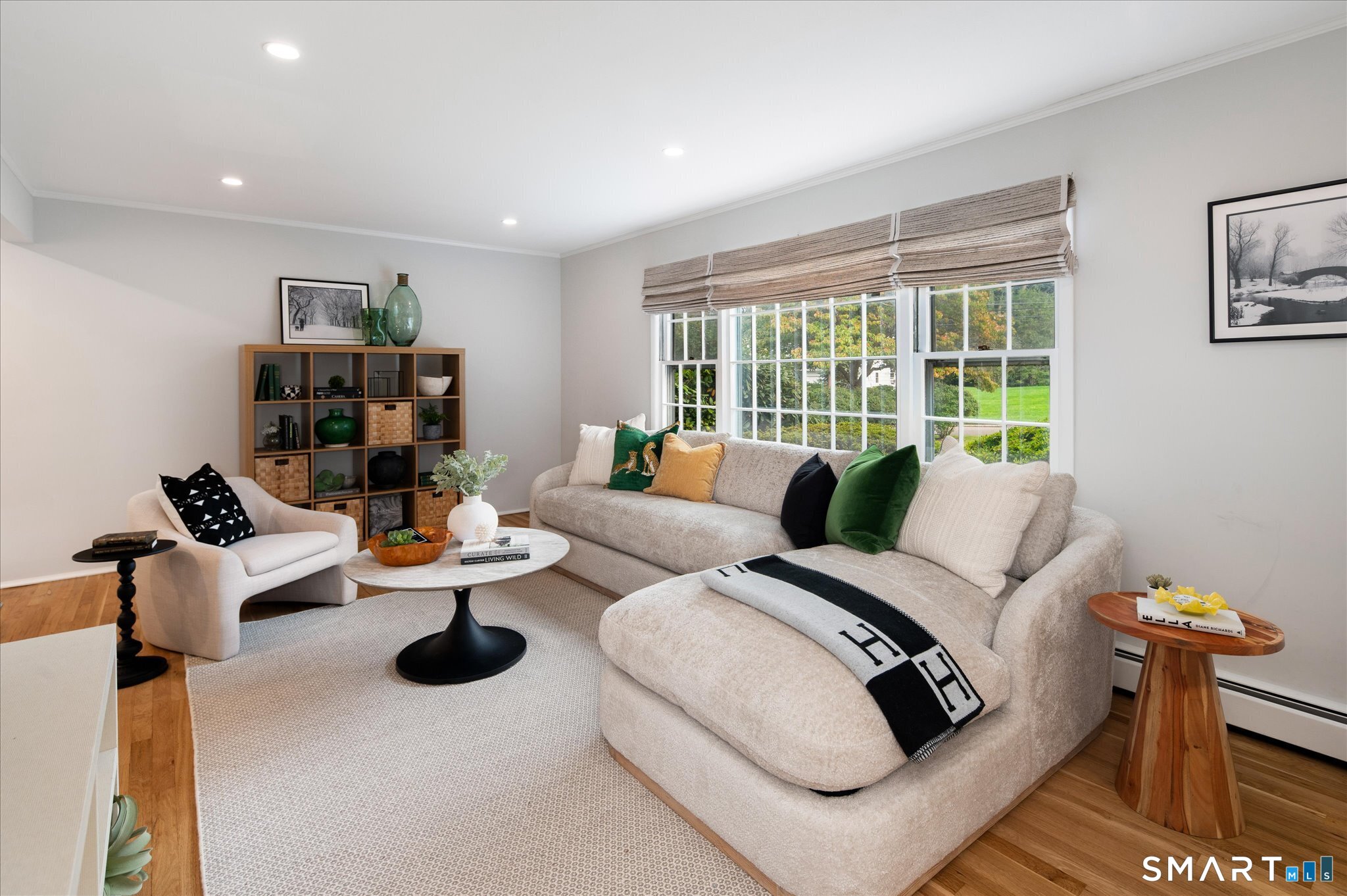 Staged living room with a cream sectional, broad windows, and views of a green yard.