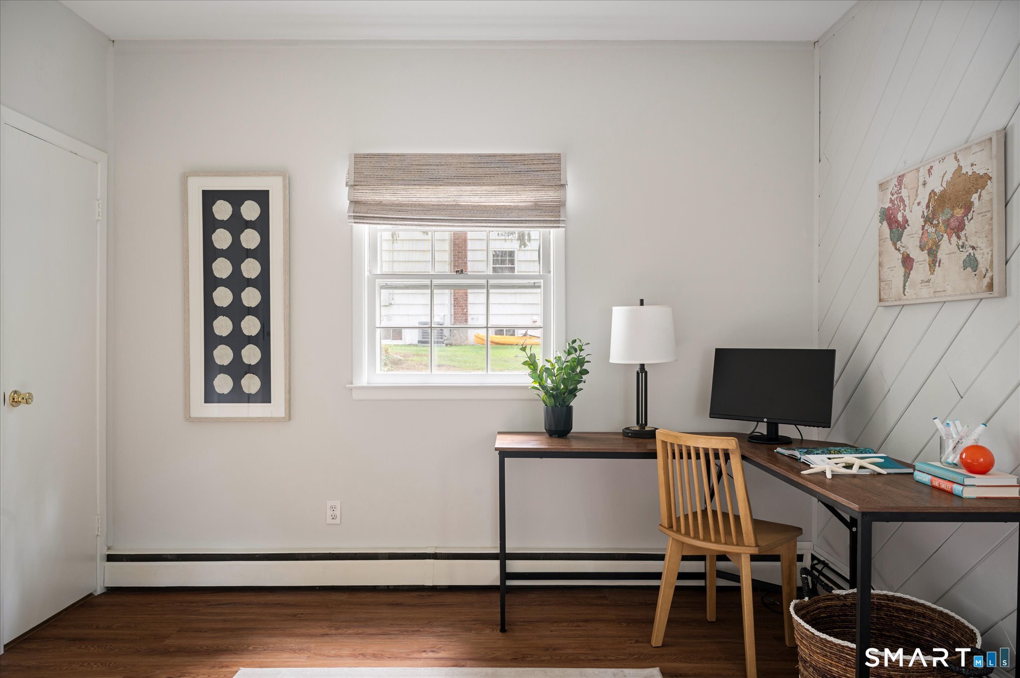 Furnished home office with a wooden desk, computer, and diagonal white wall paneling.