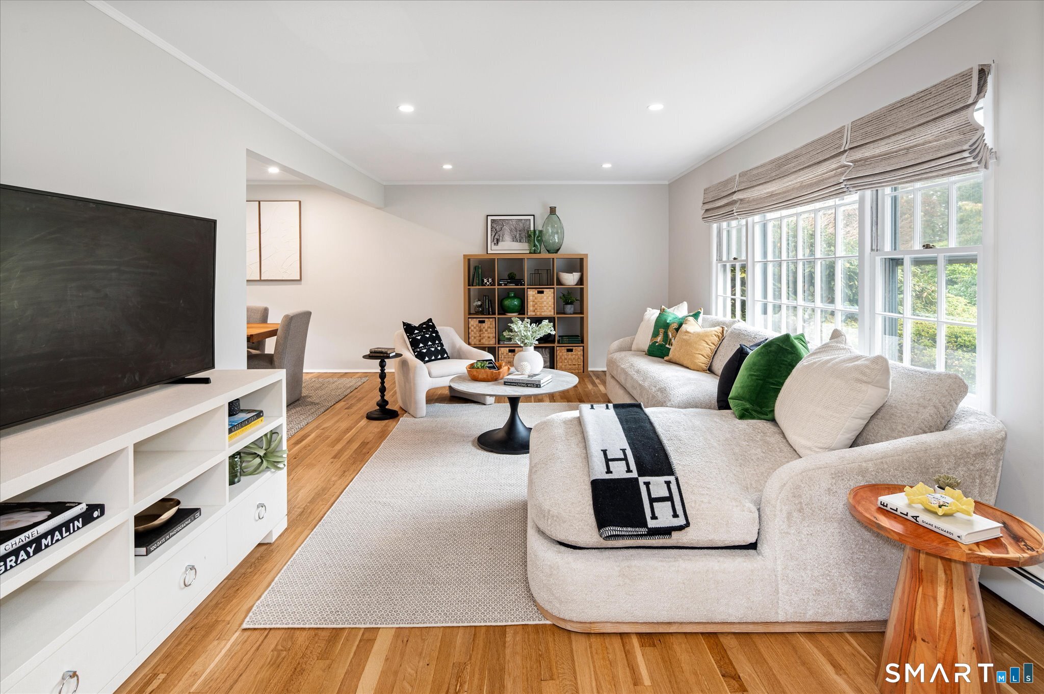 Living room with a light sectional, tall windows, hardwood floors, and an open view to the dining area.