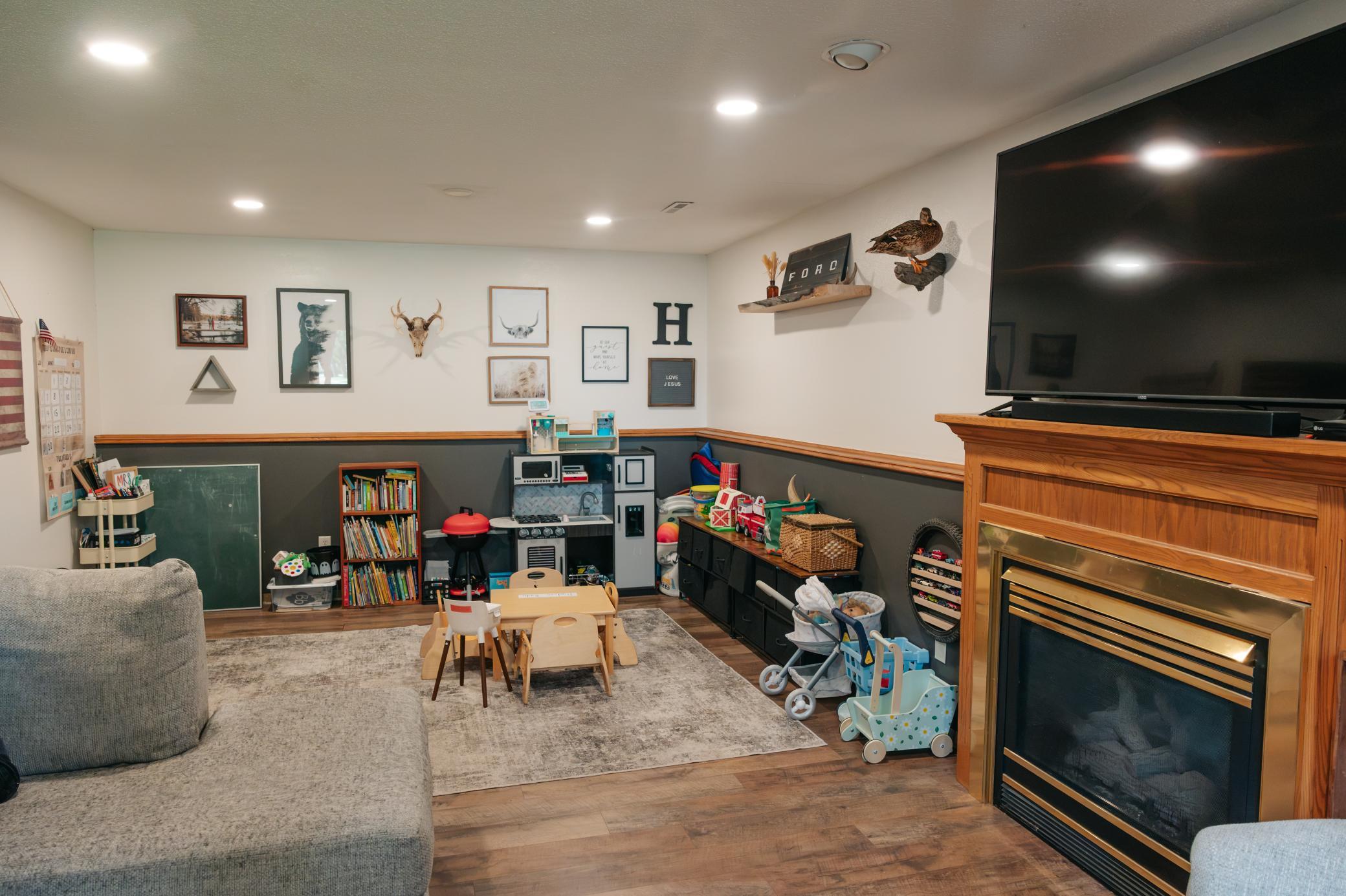 Family room with a wood fireplace, large television, and children’s play area.
