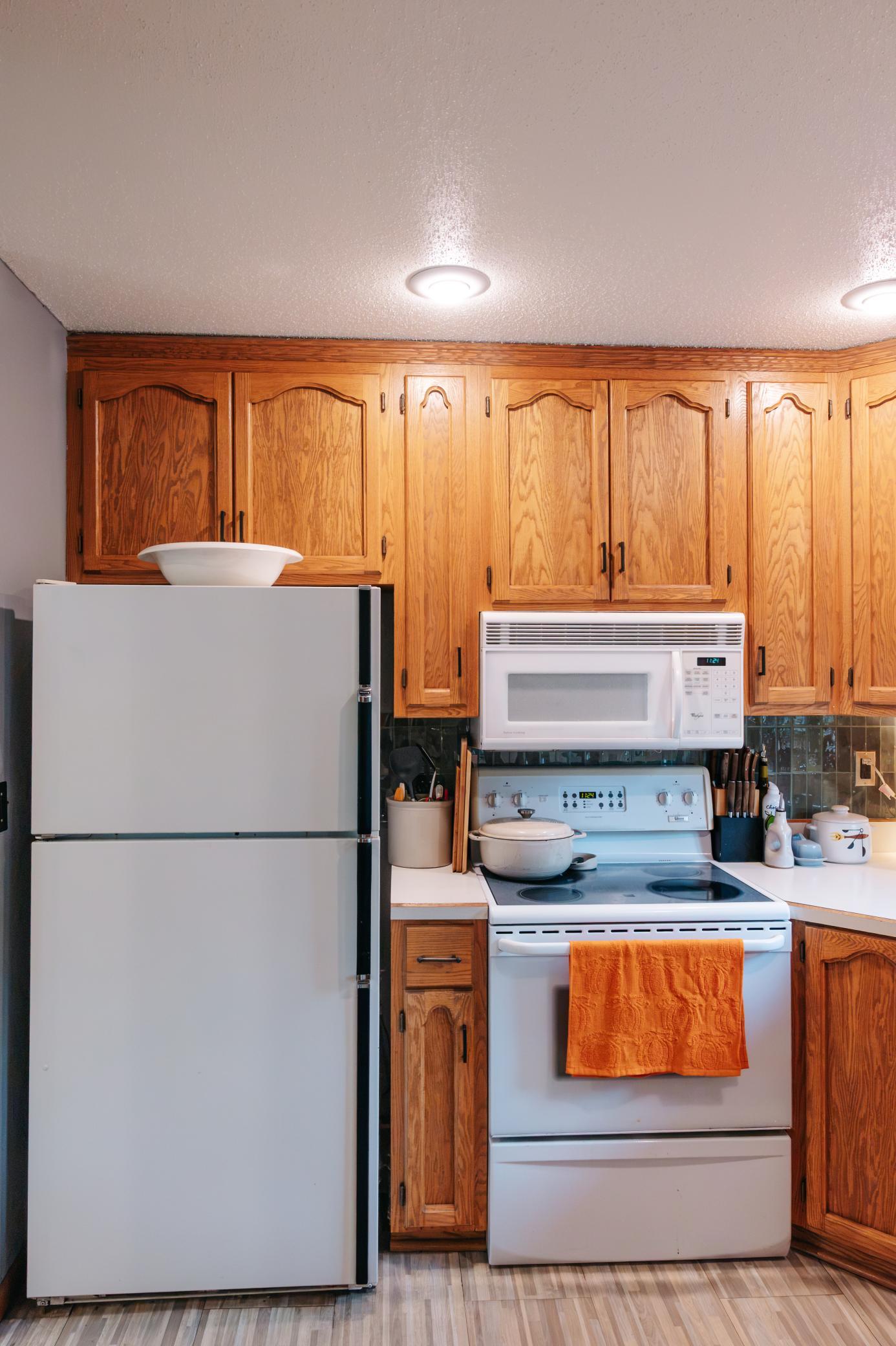 Kitchen with oak cabinets, white appliances, and an orange towel on the oven.