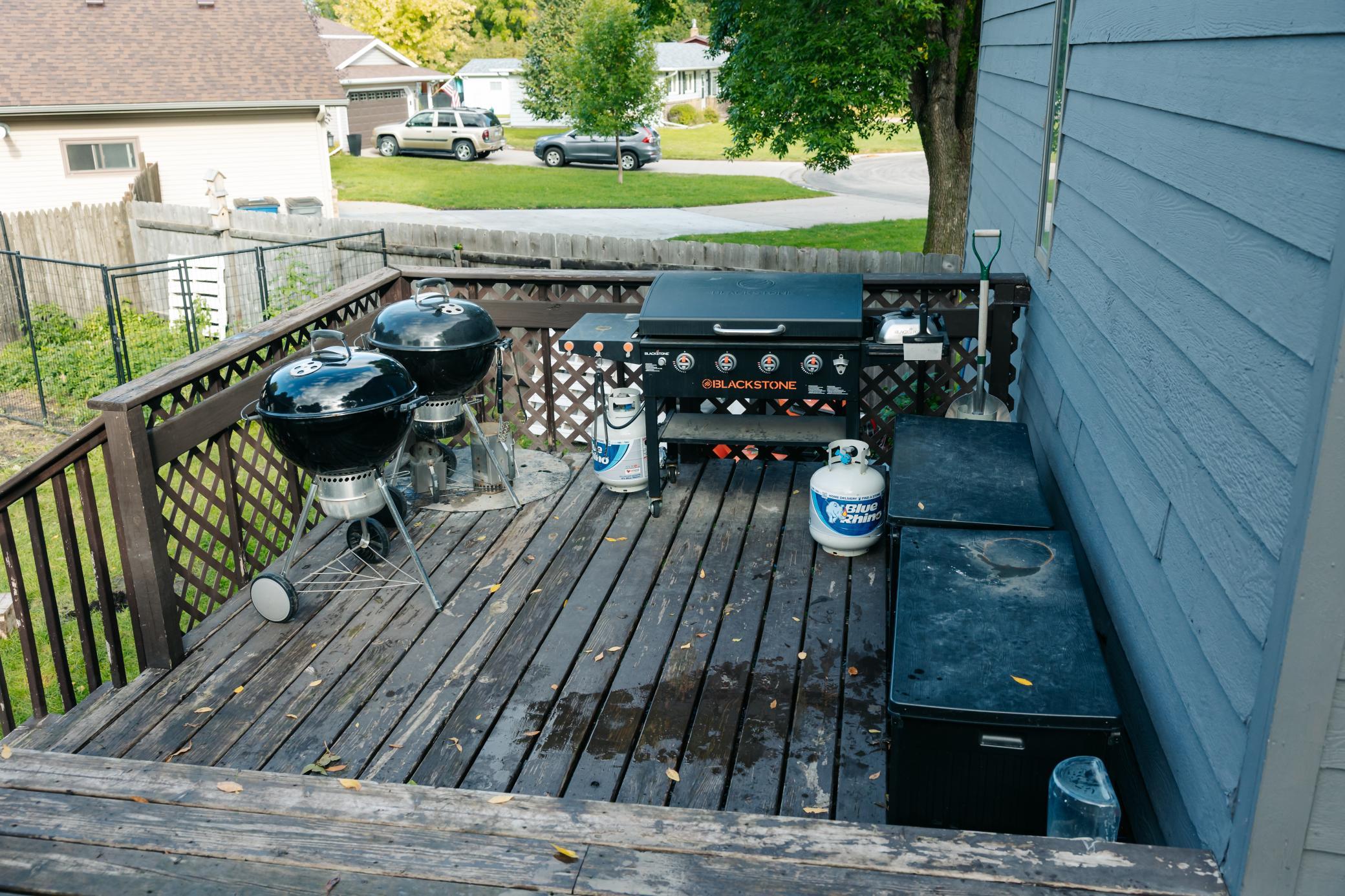 Backyard deck with two kettle grills, a Blackstone griddle, and a storage bench.