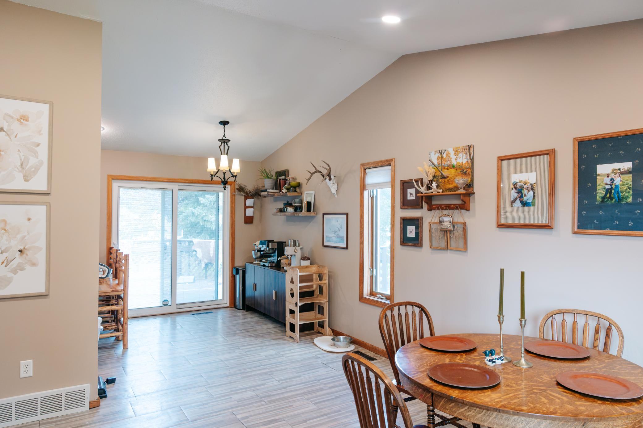 Dining area with a round wooden table, coffee station, and sliding glass doors.