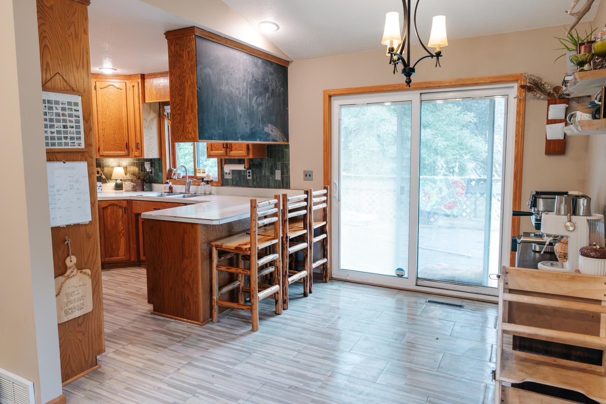 Kitchen with wood cabinets, a breakfast bar and stools, and sliding glass doors.