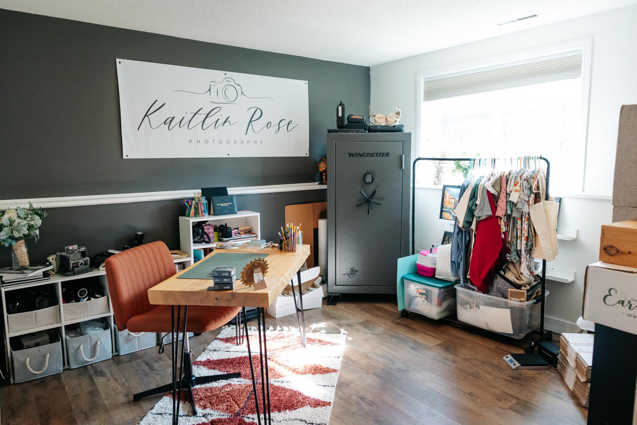 Photography studio with a wooden worktable, clothing rack, and large safe.