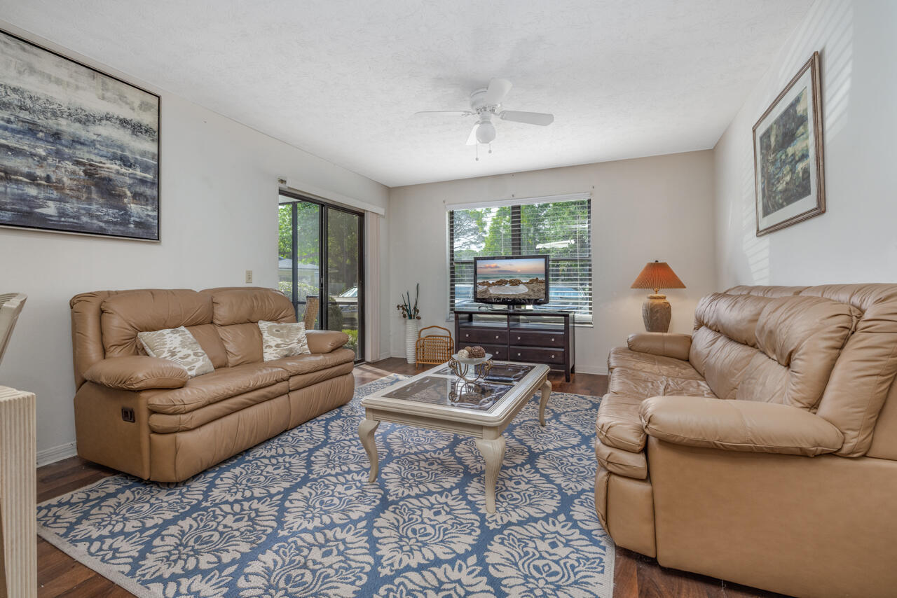 Living room with tan leather sofas, a blue patterned rug, and sliding glass doors.