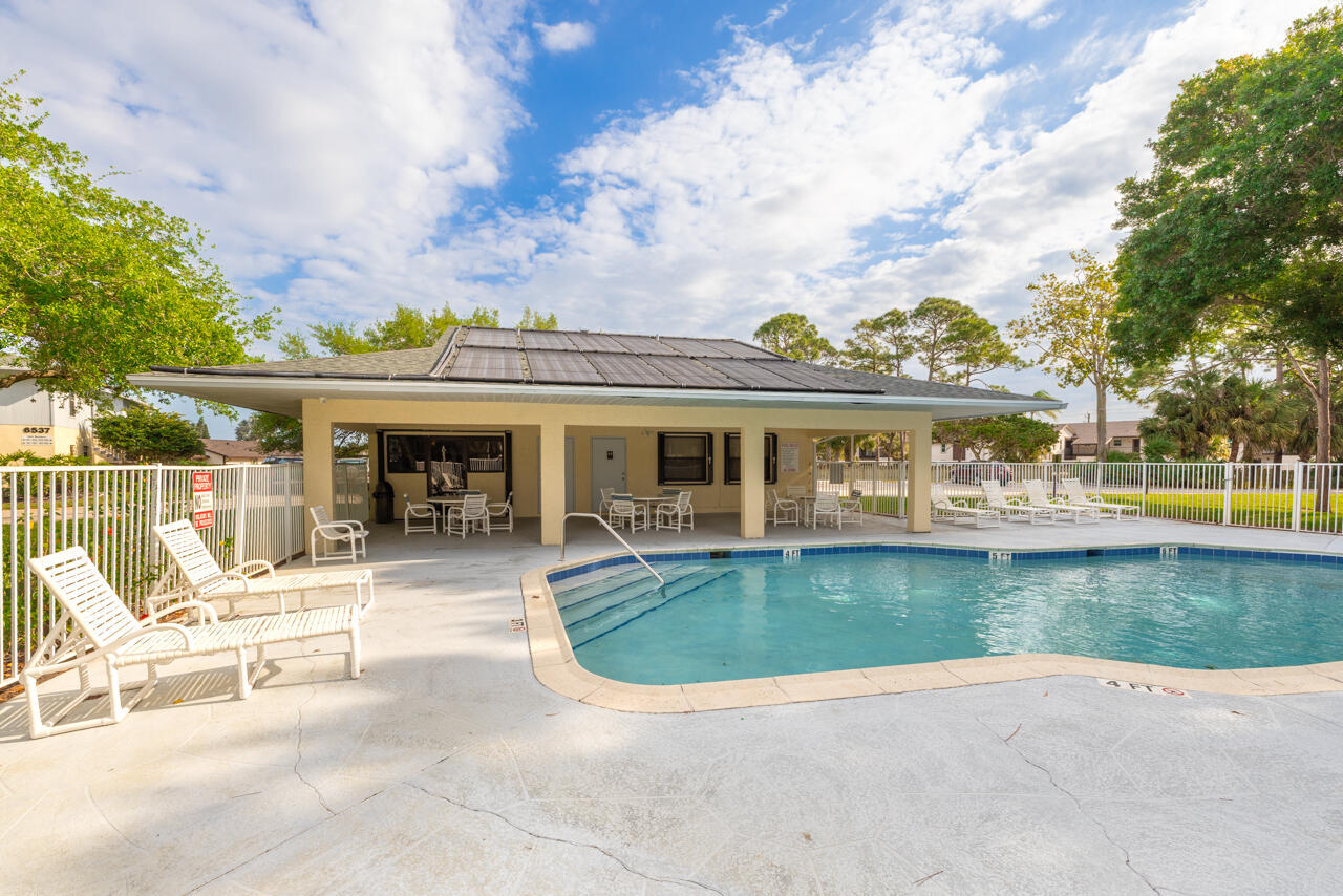 Outdoor pool beside a covered pavilion, with white lounge chairs on the surrounding deck.