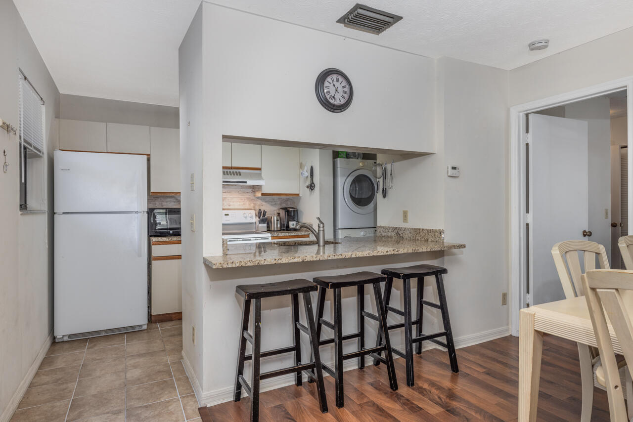 Kitchen with granite breakfast bar and stools, adjoining dining area and laundry appliances.