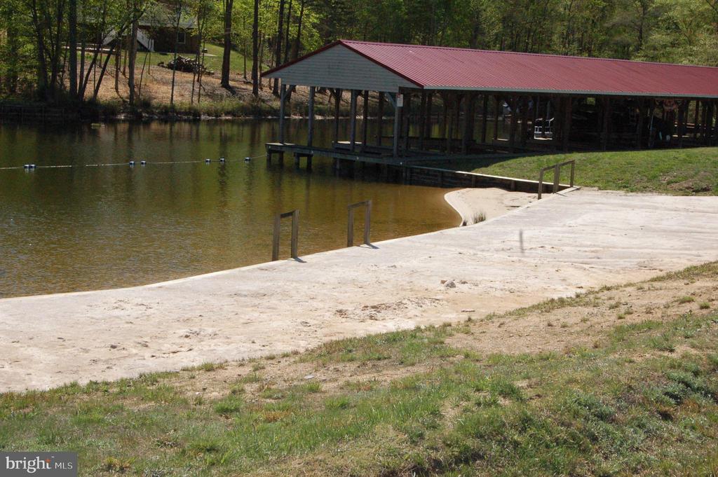 Concrete boat launch beside a lake and a covered dock with a red roof.