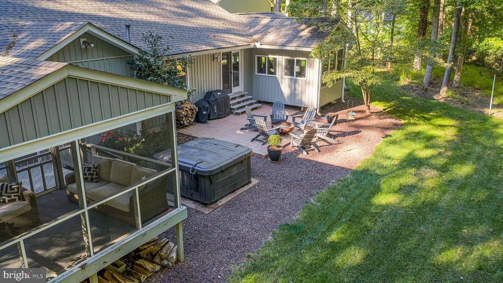 Home’s wooded backyard with a screened porch, hot tub, and patio seating.
