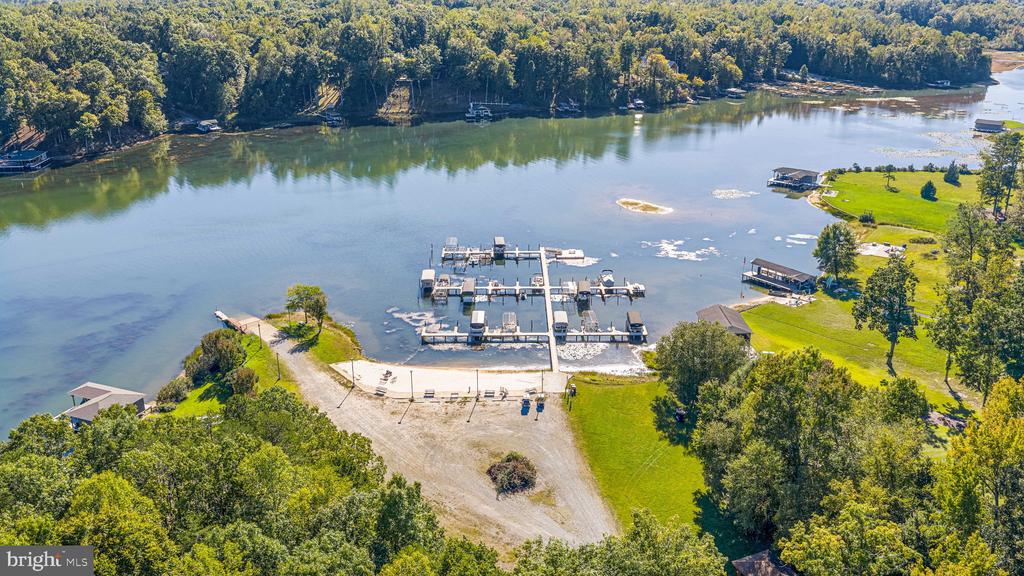 Aerial view of a lakeside marina with docks, grassy shore, and wooded shoreline.