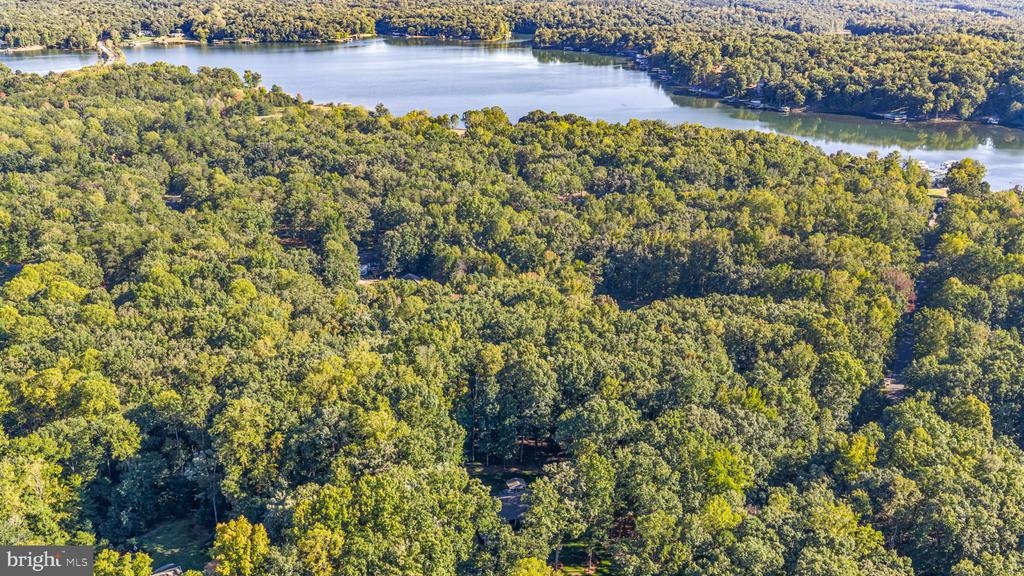 Aerial view of wooded property near a lake, with a small clearing among the trees.