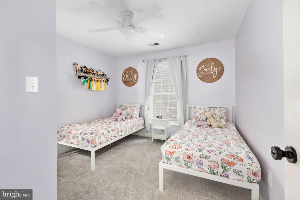 Bedroom with two twin beds in colorful floral bedding and a ceiling fan.