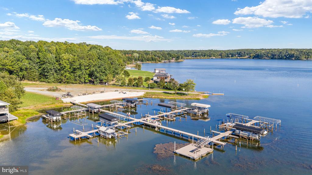 Aerial view of a lakeside marina with boat docks, wooded shoreline, and calm blue water.