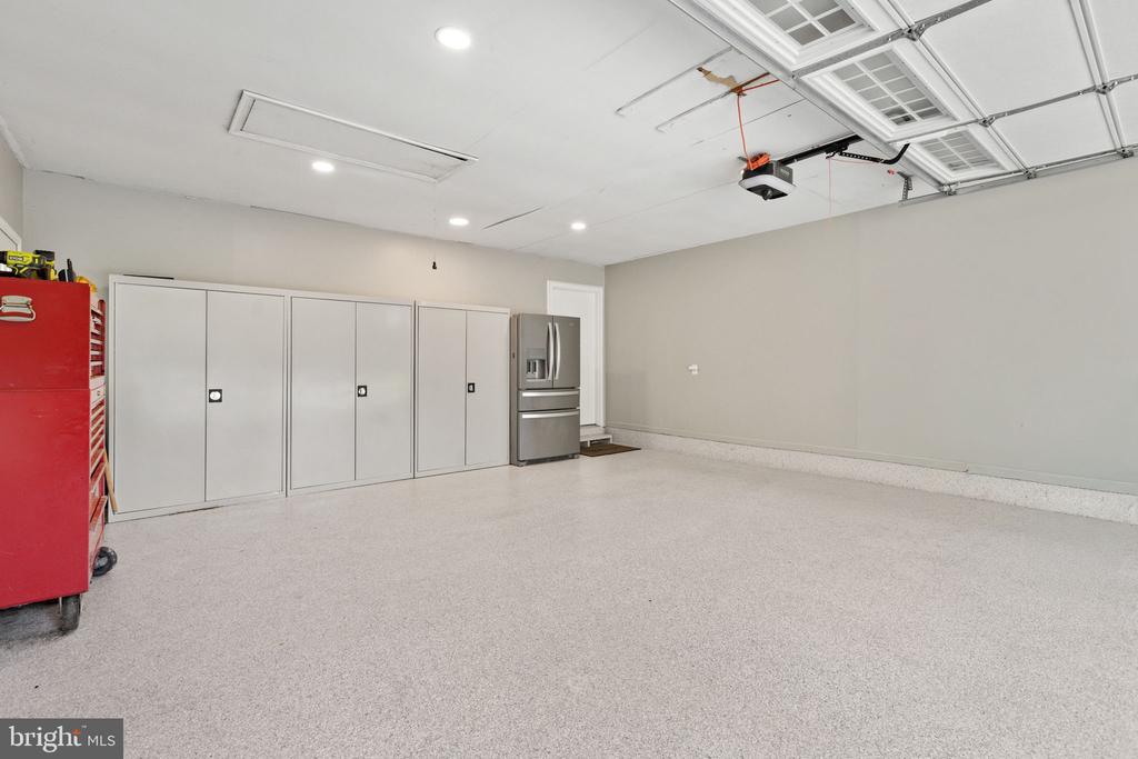 Garage with white storage cabinets, a stainless steel refrigerator, and a red tool chest.