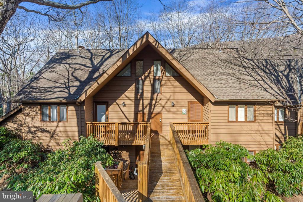 Wood-sided house with a prominent gable and elevated deck connected to a long wooden ramp.