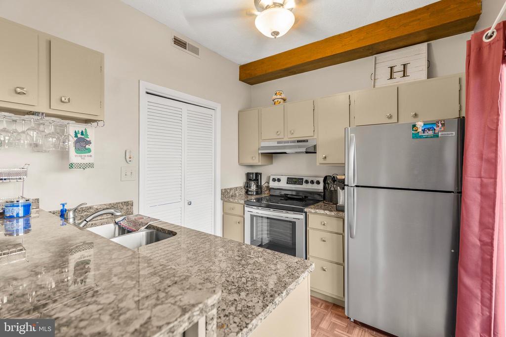 Kitchen with granite counters, stainless steel appliances, and an exposed wooden ceiling beam.