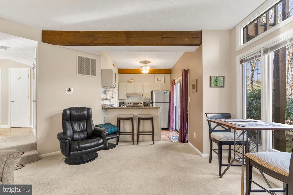 Open living area with a leather recliner, breakfast bar, and tall windows beside the dining table.