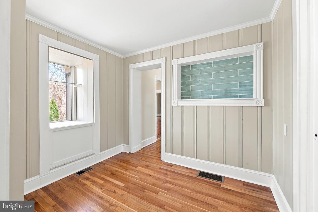 Empty room with beige paneled walls, hardwood floors, and a framed teal tile inset.