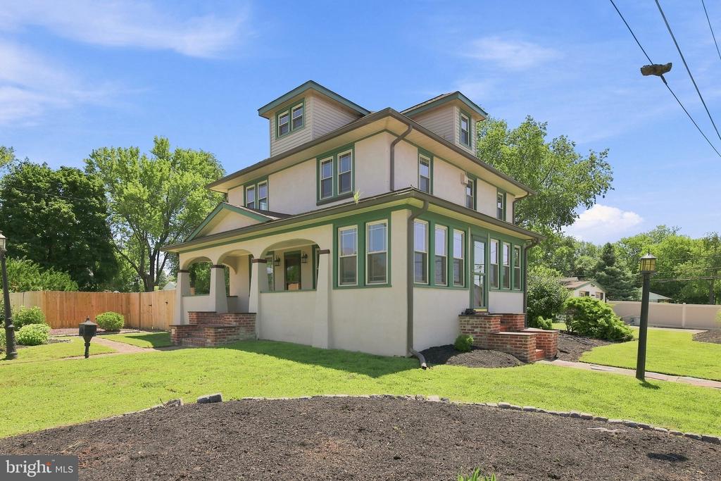 Multi-story cream home with green trim, two dormers, and a covered front porch.