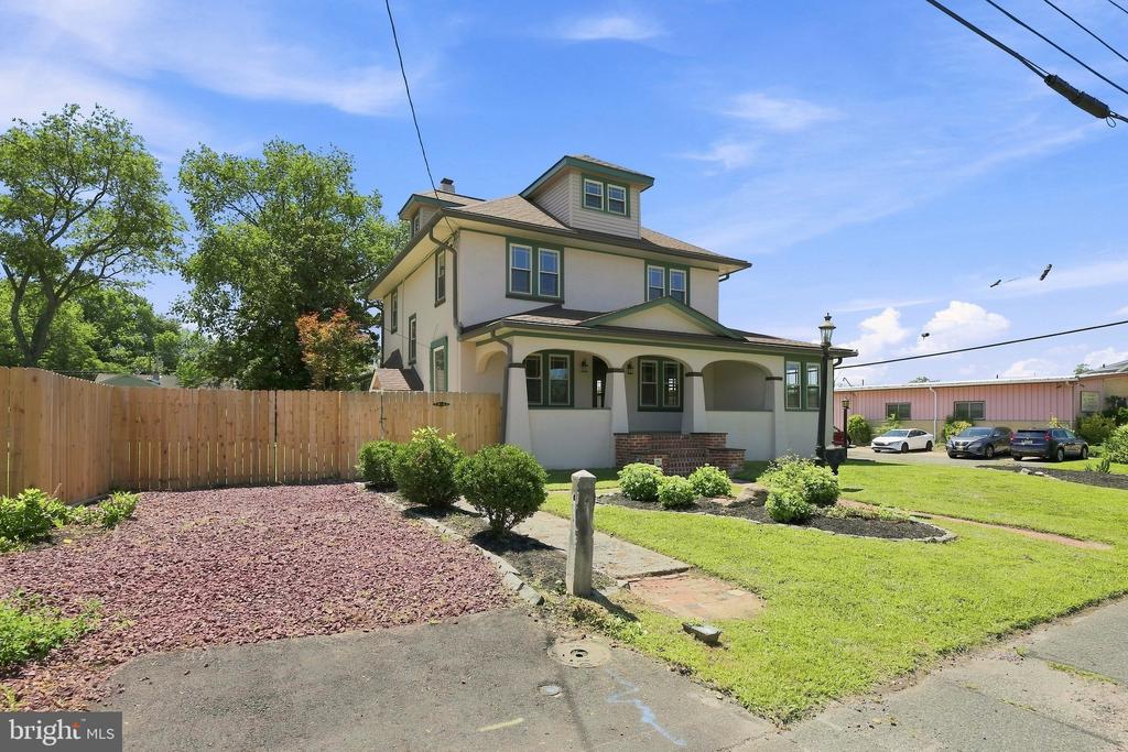 Two-story house with a covered porch, green trim, and a fenced side yard.