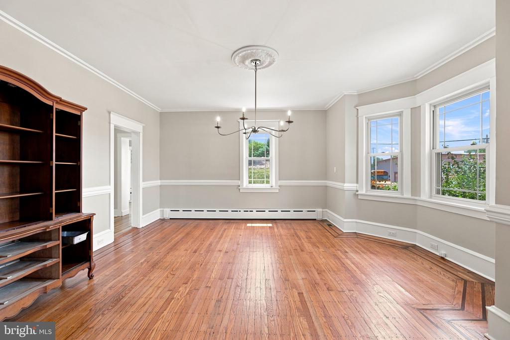 Empty dining room with hardwood floors, a chandelier, and large windows.