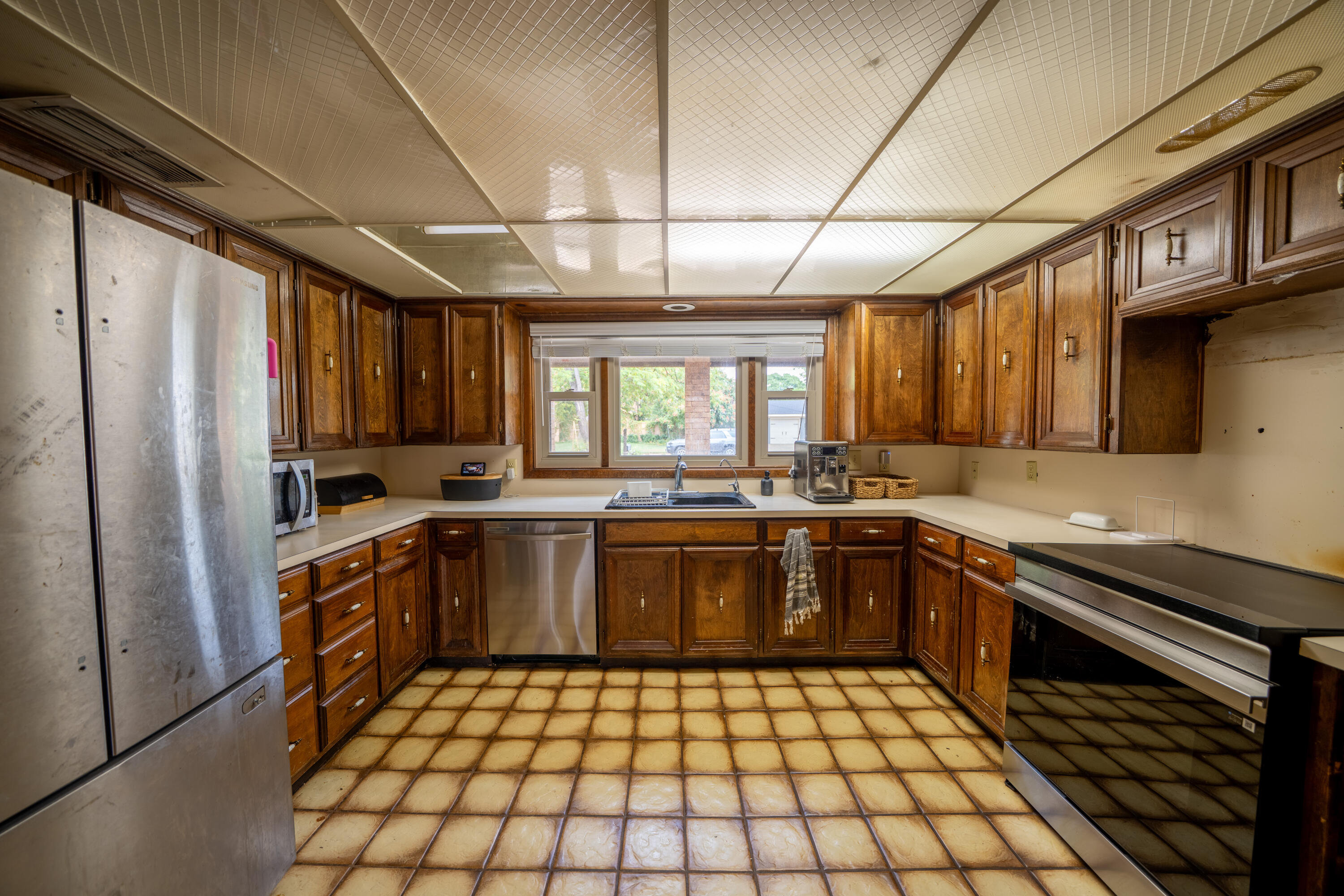Kitchen with dark wood cabinets, stainless steel appliances, and a sink beneath a wide window.