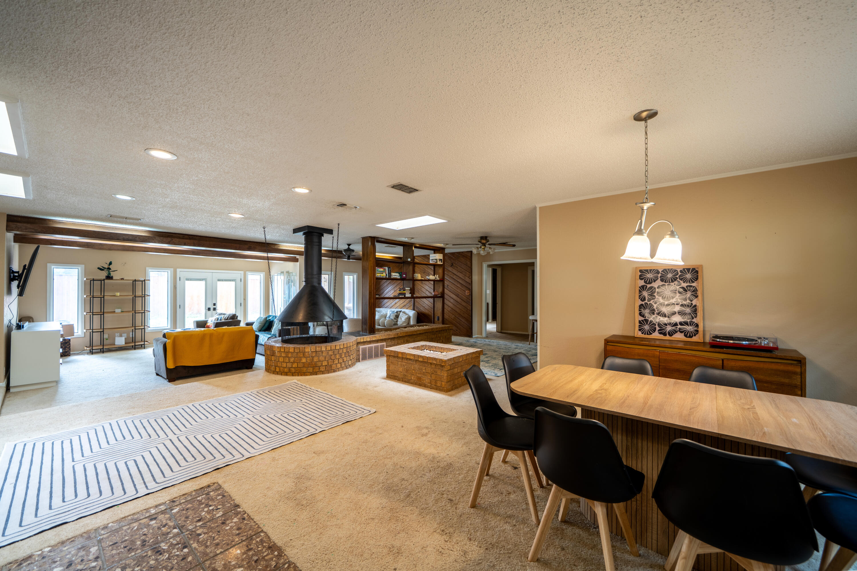 Open-plan living and dining room with a suspended fireplace above a round brick hearth.