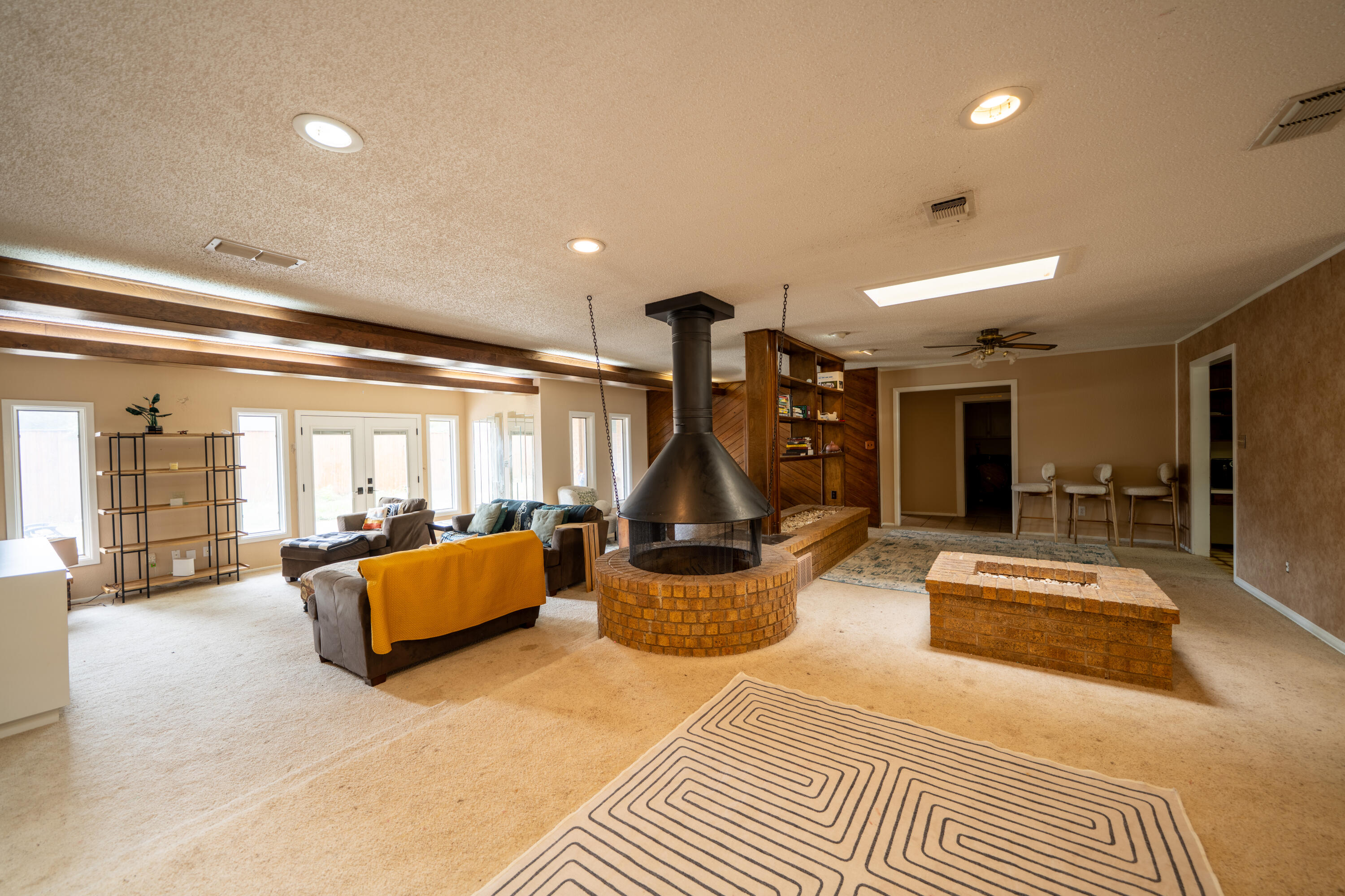 Living room with a suspended fireplace, circular brick hearth, built-in shelves, and large windows.