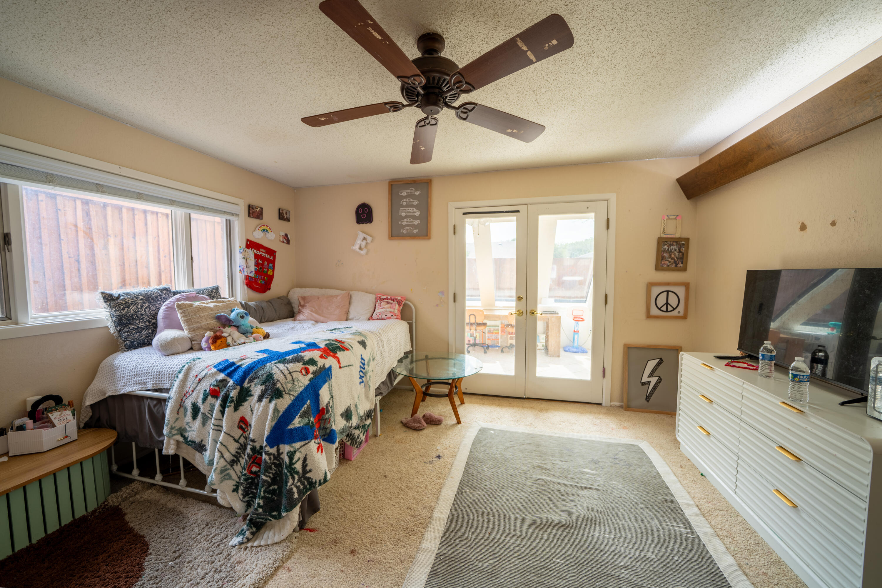 Furnished bedroom with a daybed, ceiling fan, and glass doors opening to a patio.