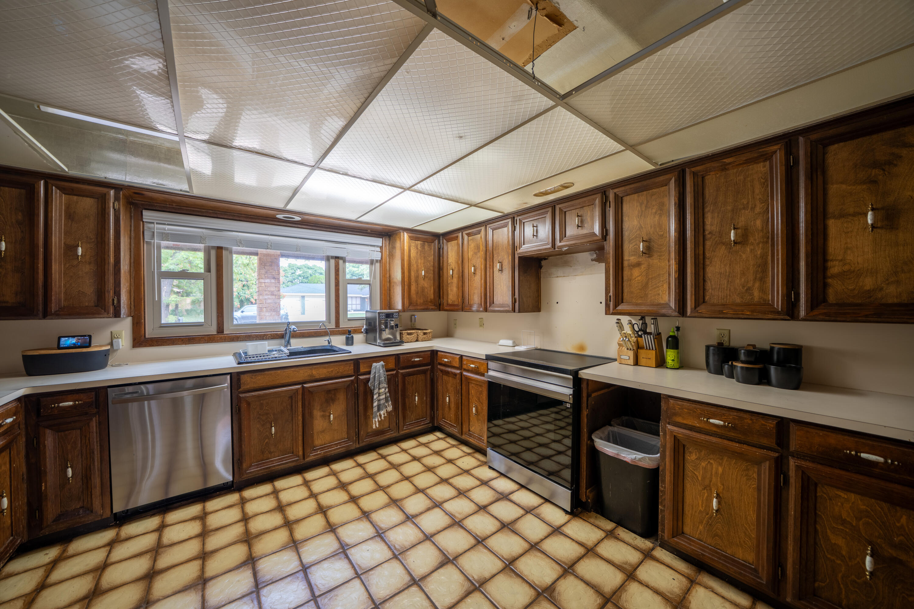 Kitchen with dark wood cabinets, tan tile floors, and a large window over the sink.