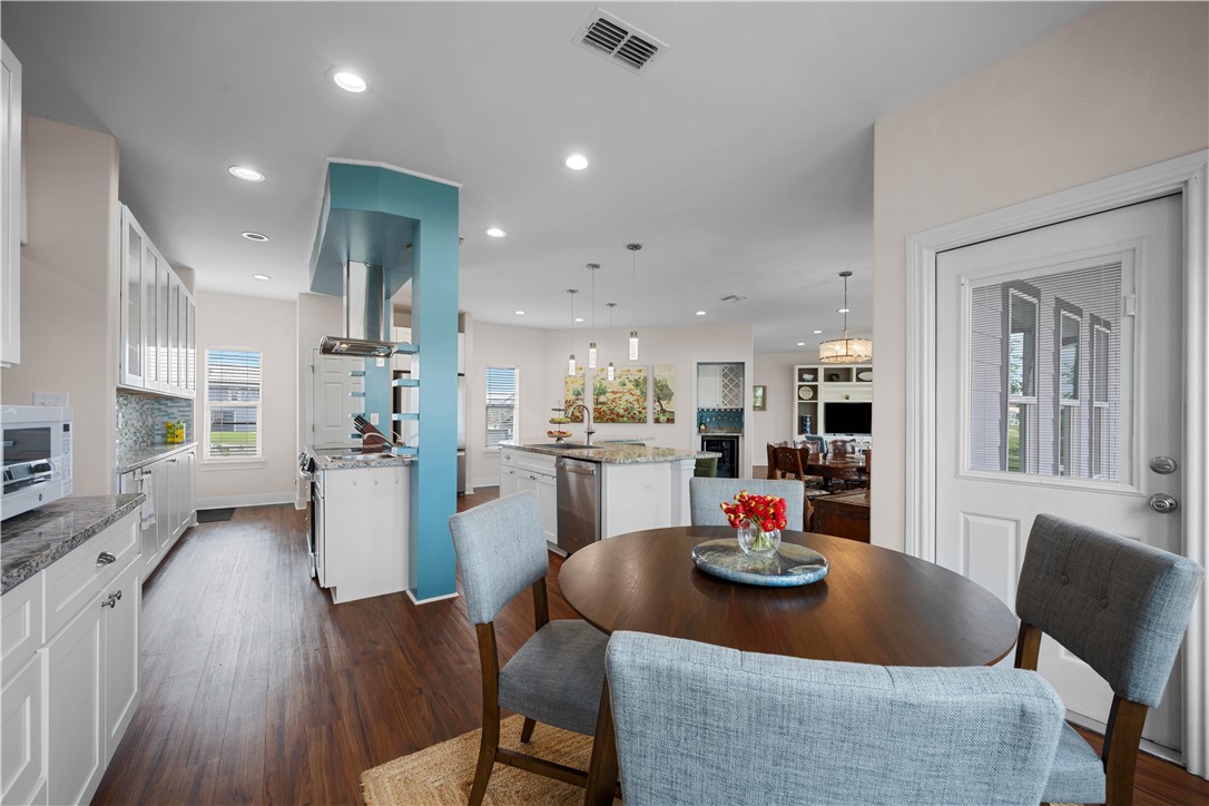 Open-plan kitchen and dining area with a turquoise range hood and round wooden table.